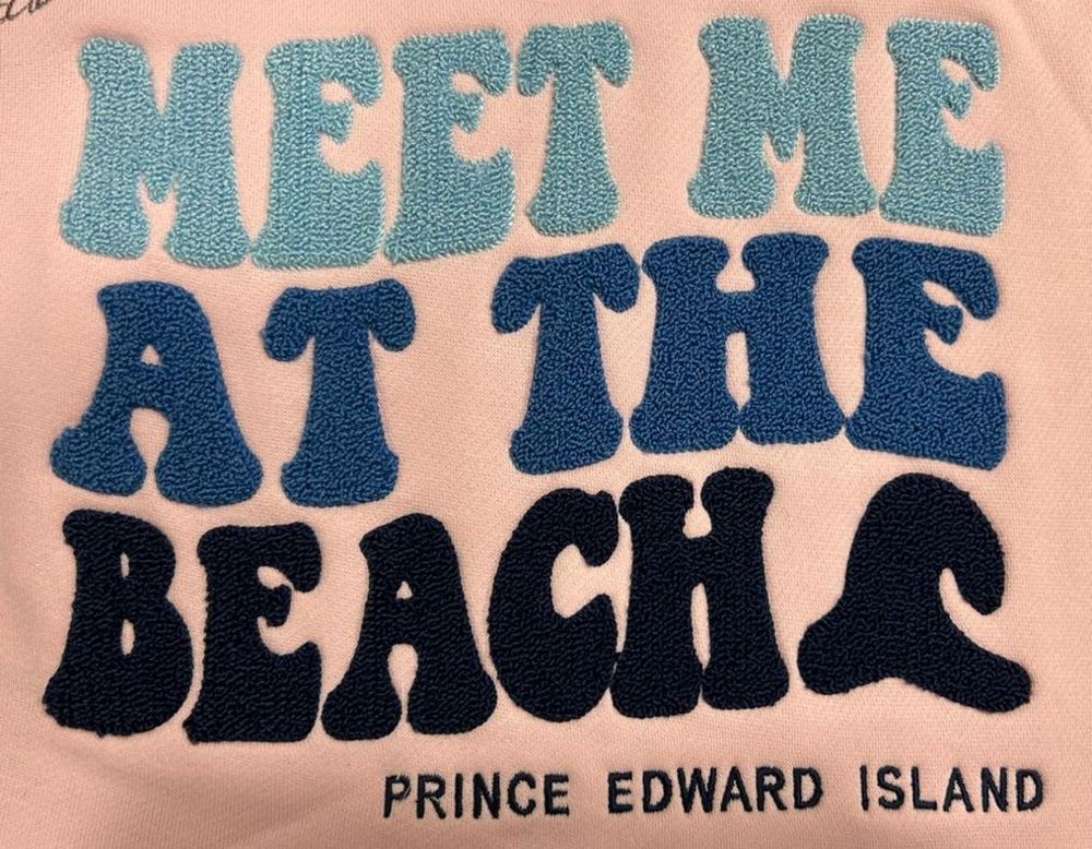 Multi-color chenille embroidery reading Meet Me At The Beach on a pink crewneck sweatshirt