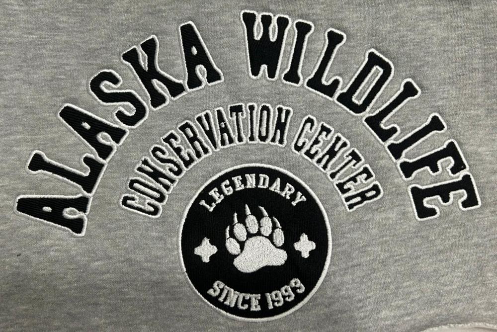 Self-fabric applique reading Alaska Wildlife Conservation Center on a grey heather sweatshirt